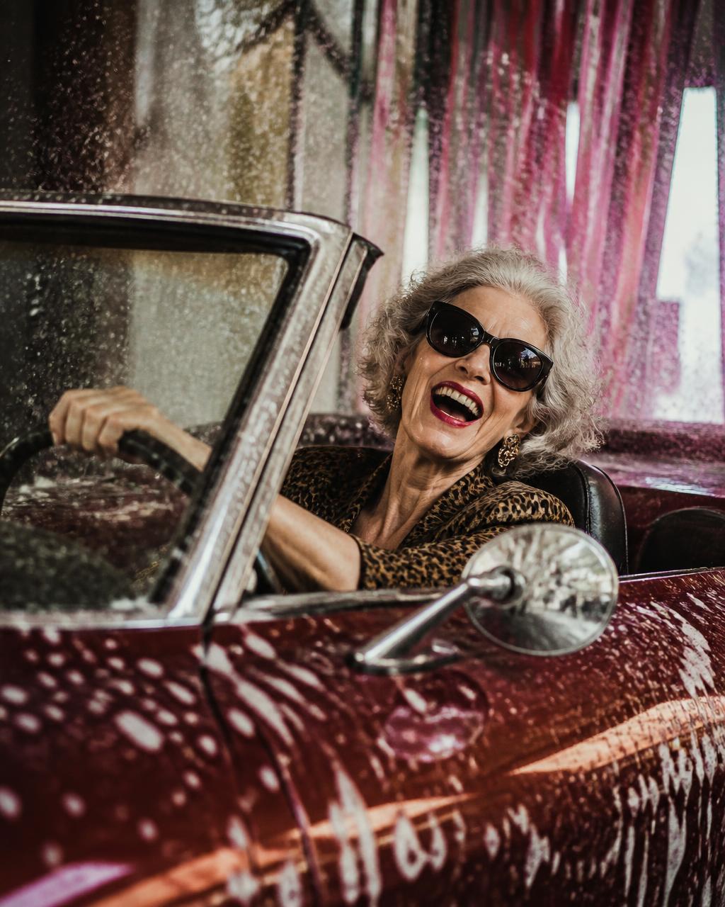 Older woman laughing in a convertible during a car wash