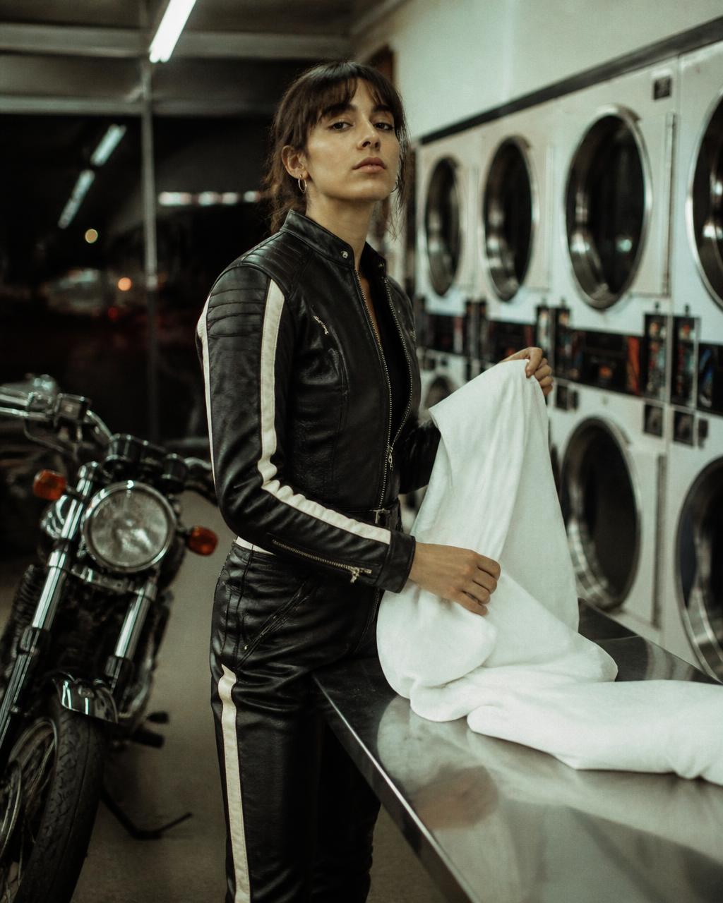 Woman in motorcycle leathers folding sheets in a laundromat