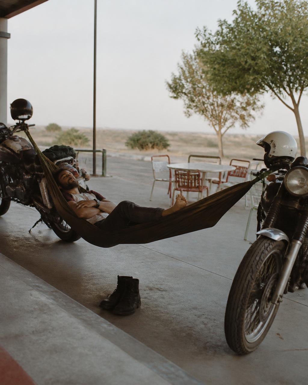 Man napping in a hammock strung between two motorcycles