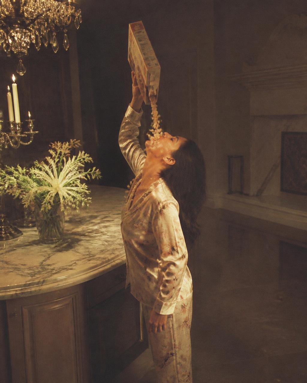 Woman in pajamas eating cereal from the box in a fancy kitchen at midnight