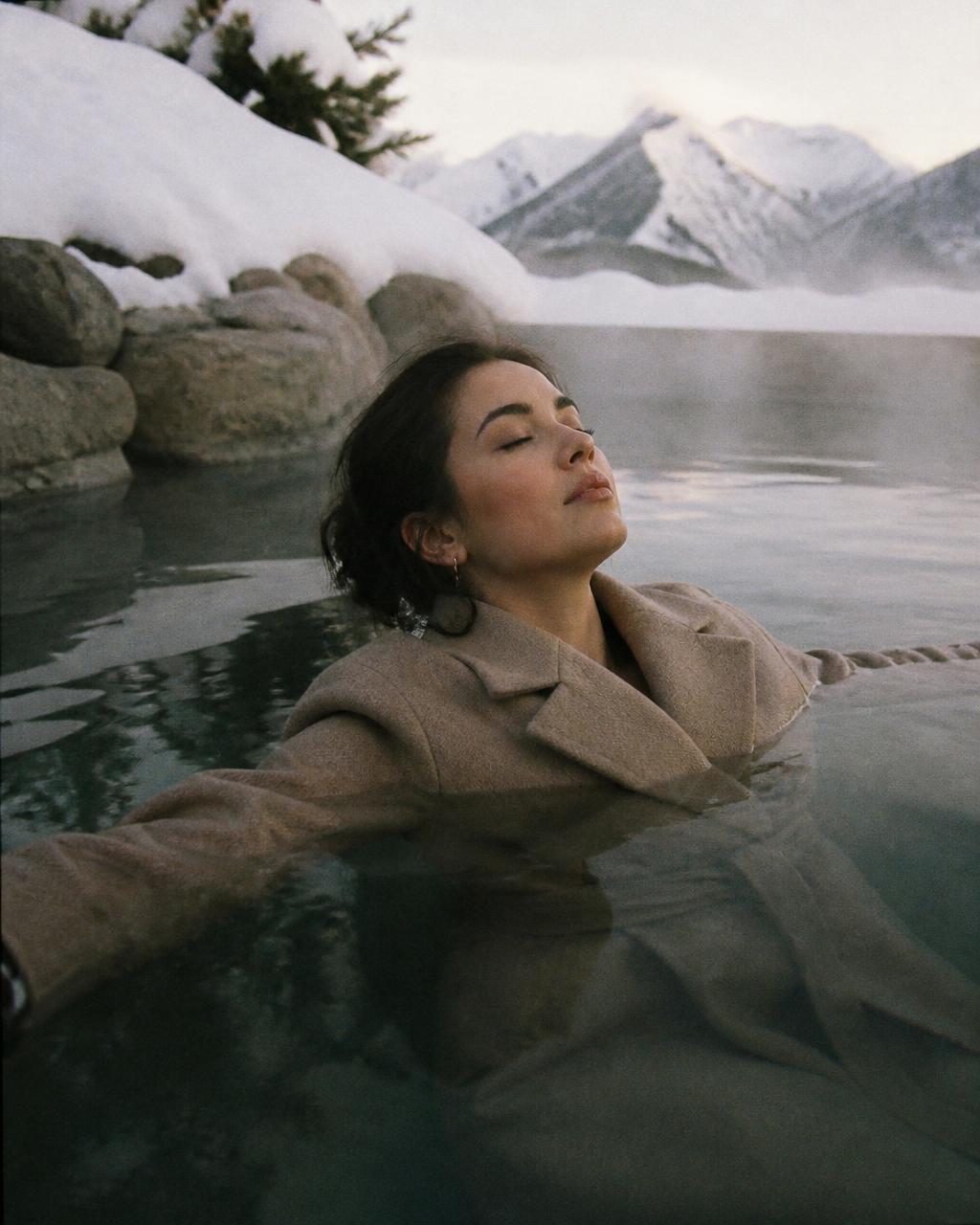 Woman floating peacefully in a winter lake in her overcoat