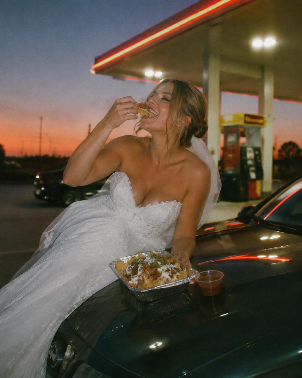 Bride eating gas station nachos on a car hood at dusk