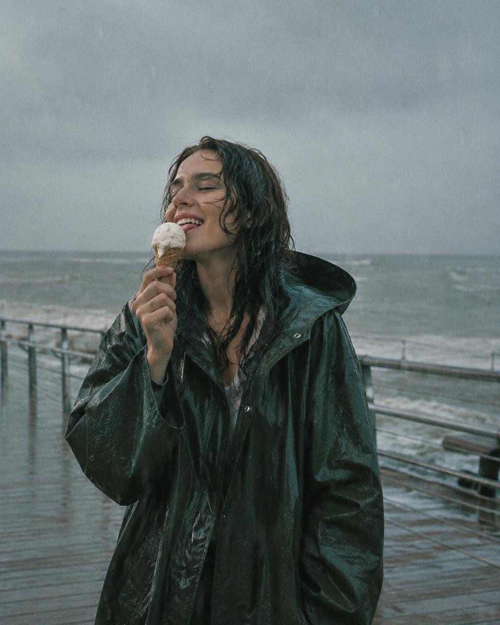 Woman eating ice cream in the rain on a boardwalk