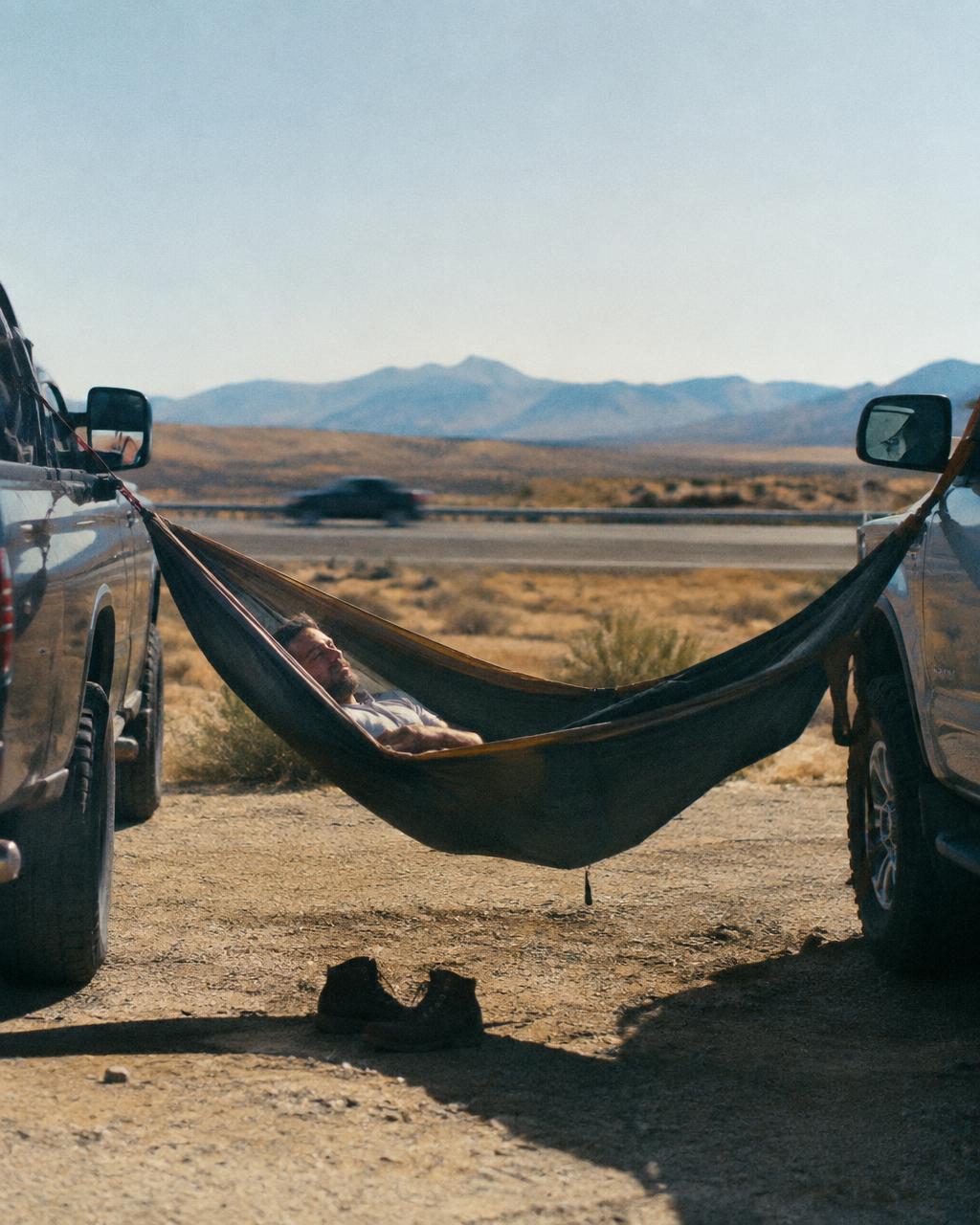 Man napping in a hammock strung between two trucks