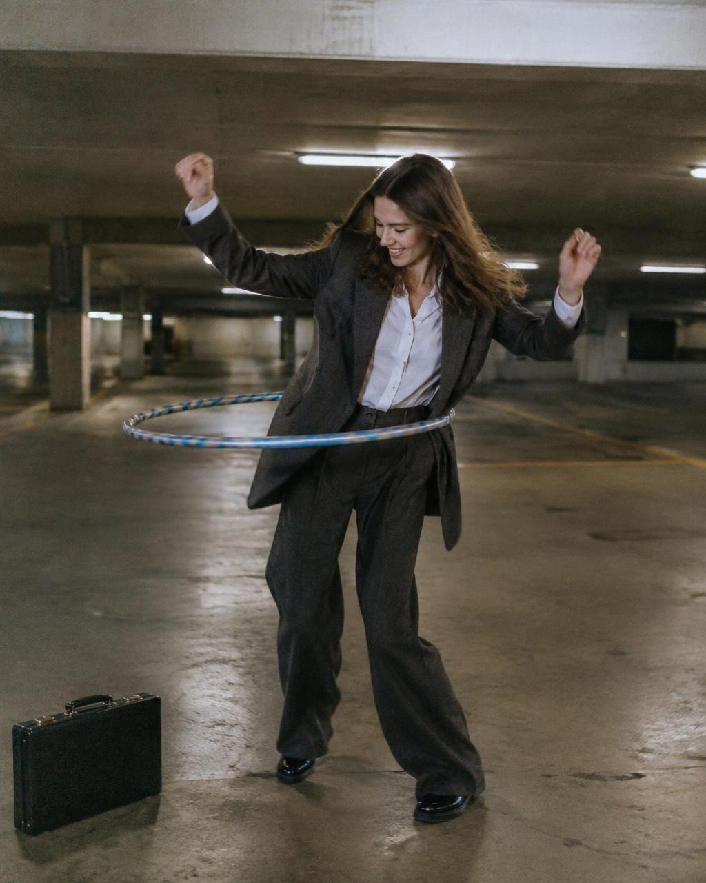 Woman in a pantsuit hula hooping in a parking garage