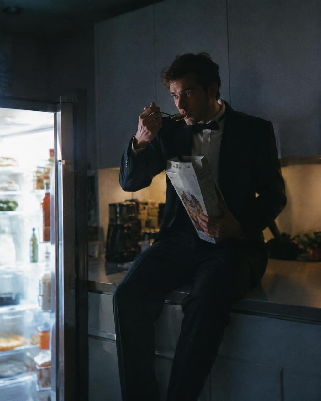 Man in a tuxedo eating cereal from the box at 3am