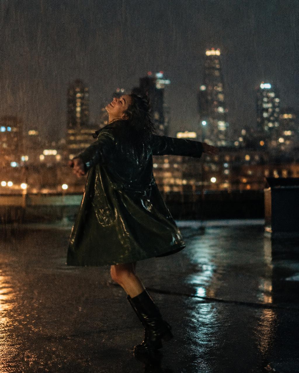 Woman spinning in the rain on a rooftop at night