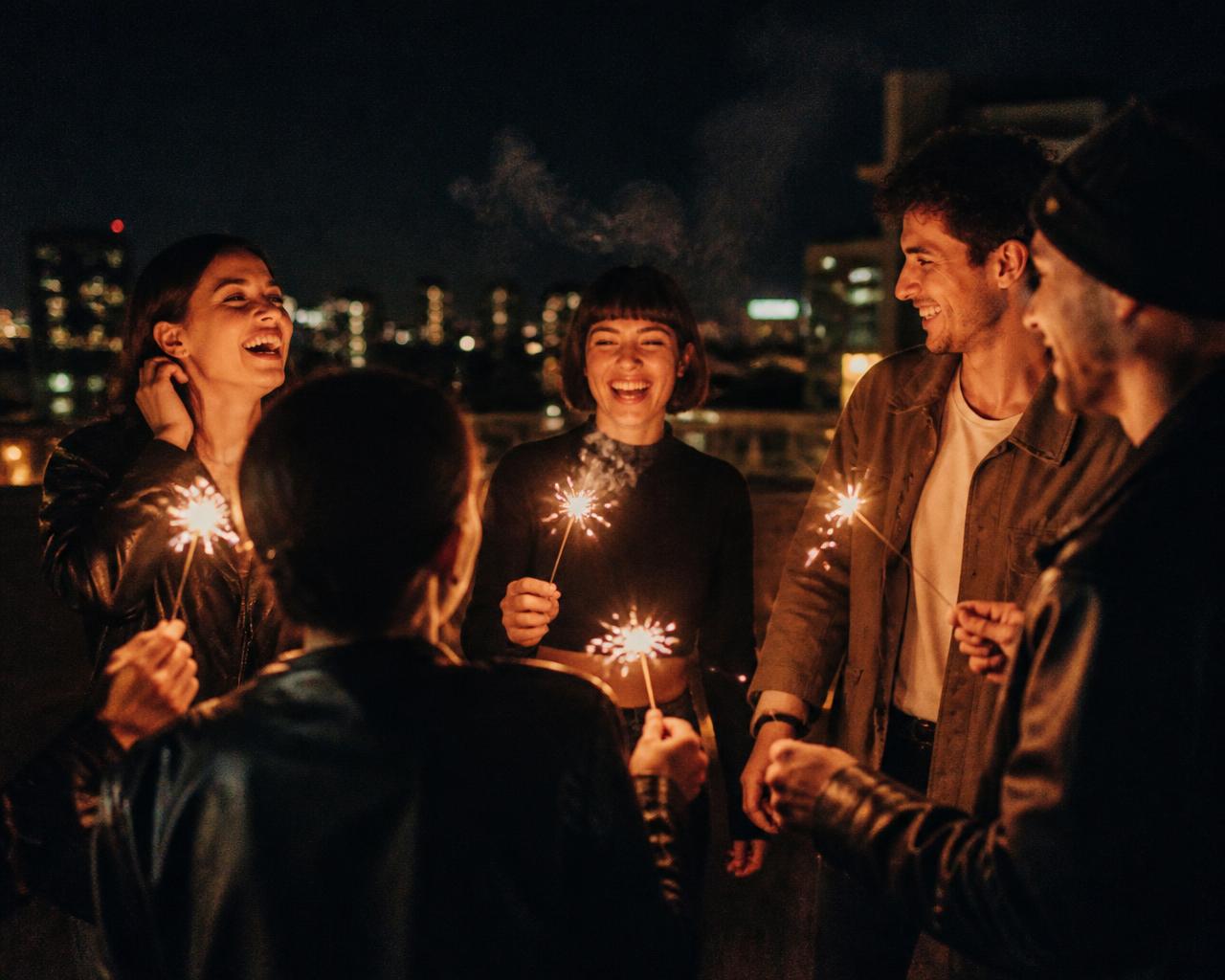 Friends with sparklers on a rooftop at night