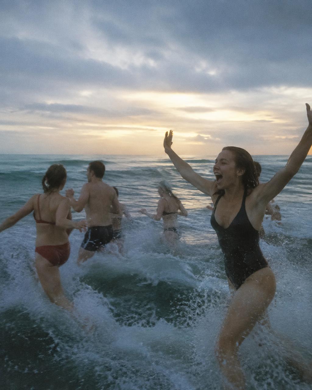 Group sprinting into a cold grey ocean at dawn