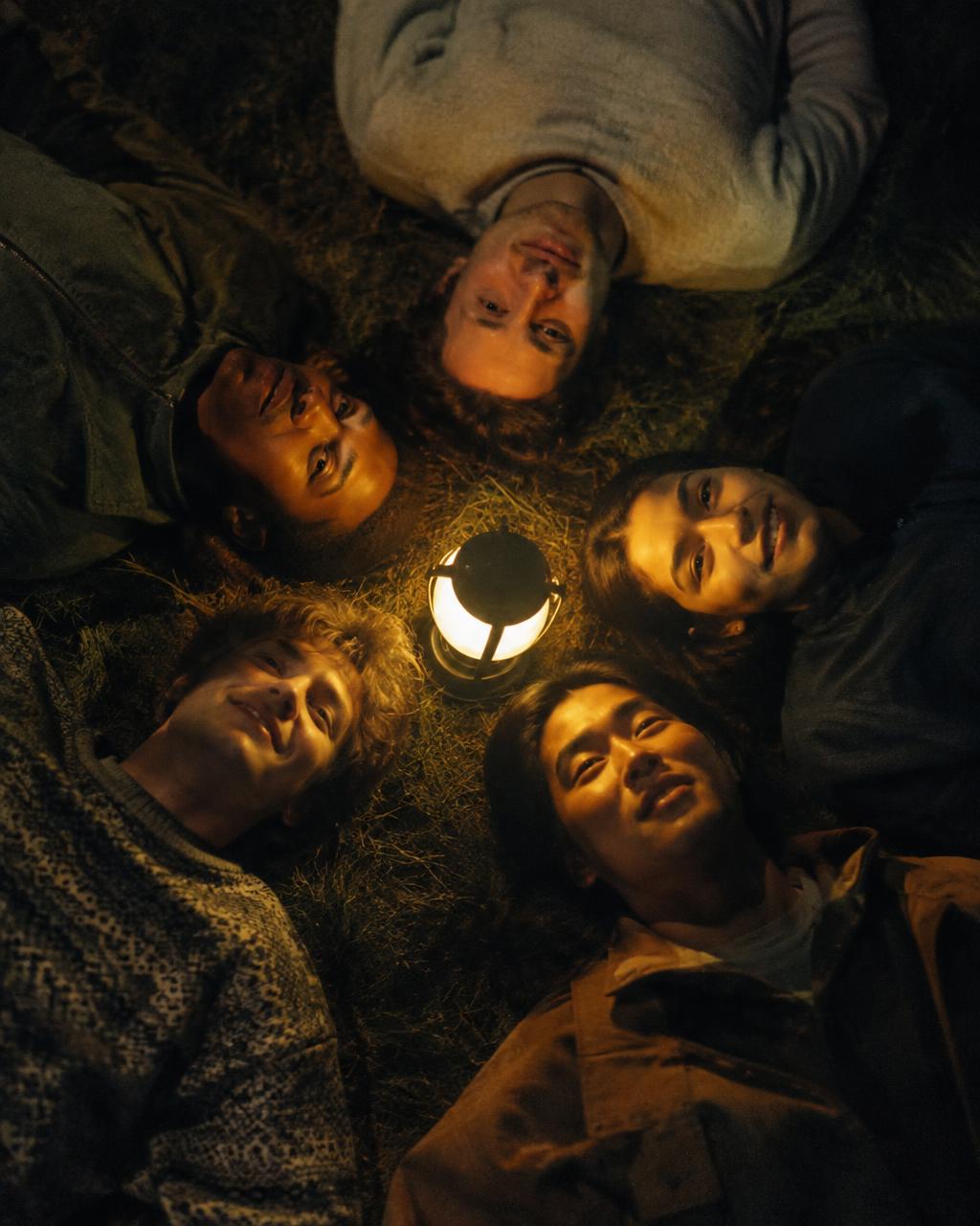 Friends lying in a circle on grass at night