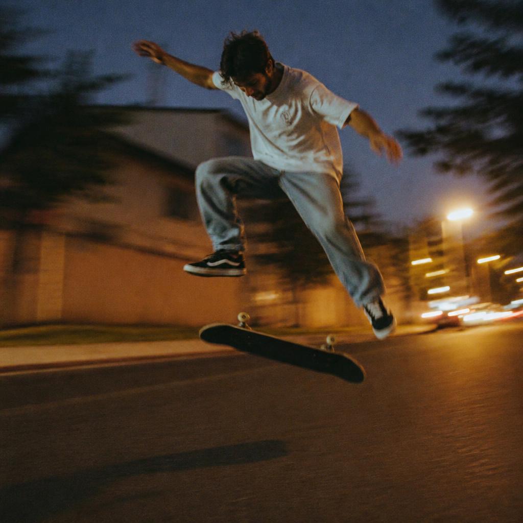 Skateboarder mid-kickflip on a dusk street with motion blur