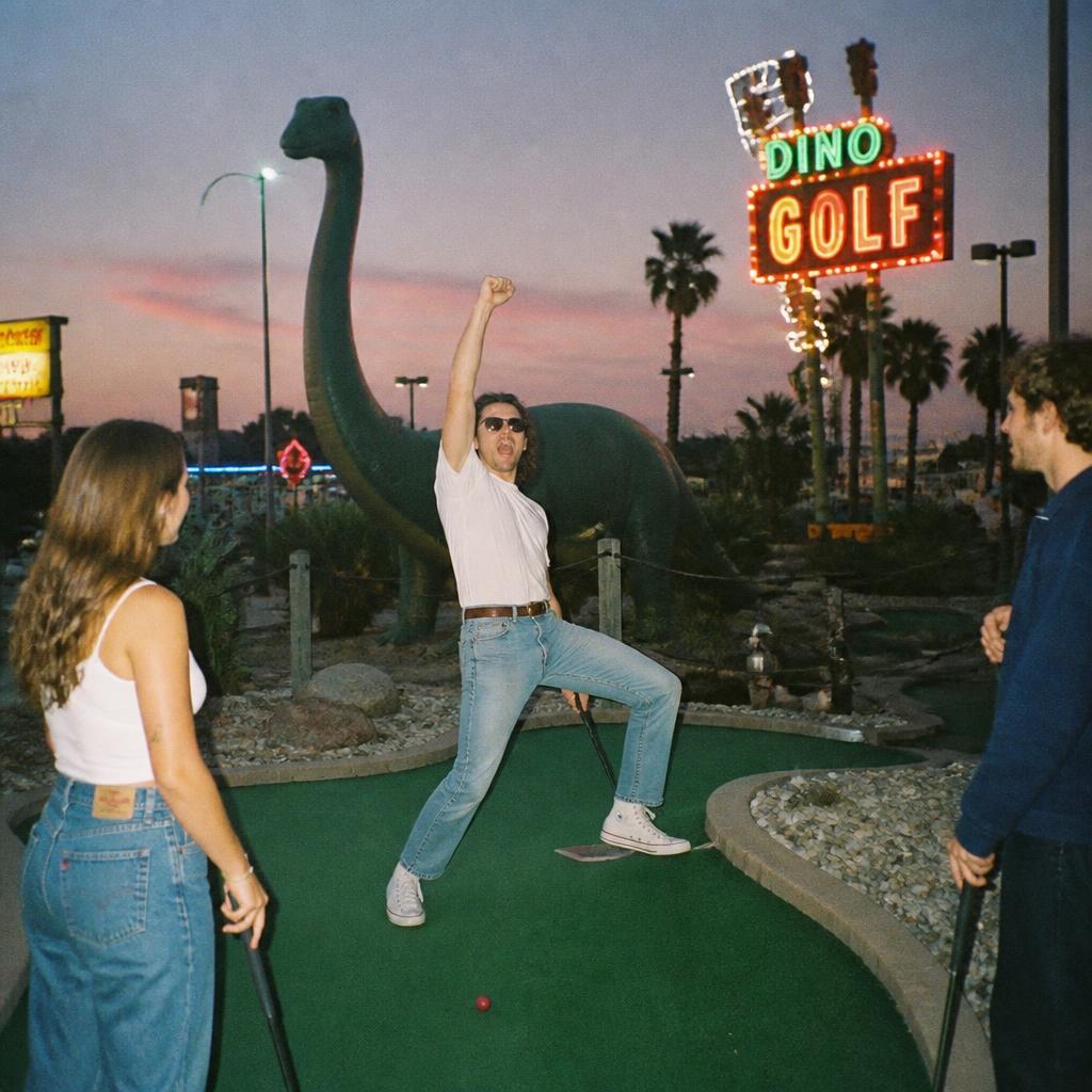 Friends playing mini golf at dusk with absurd celebration