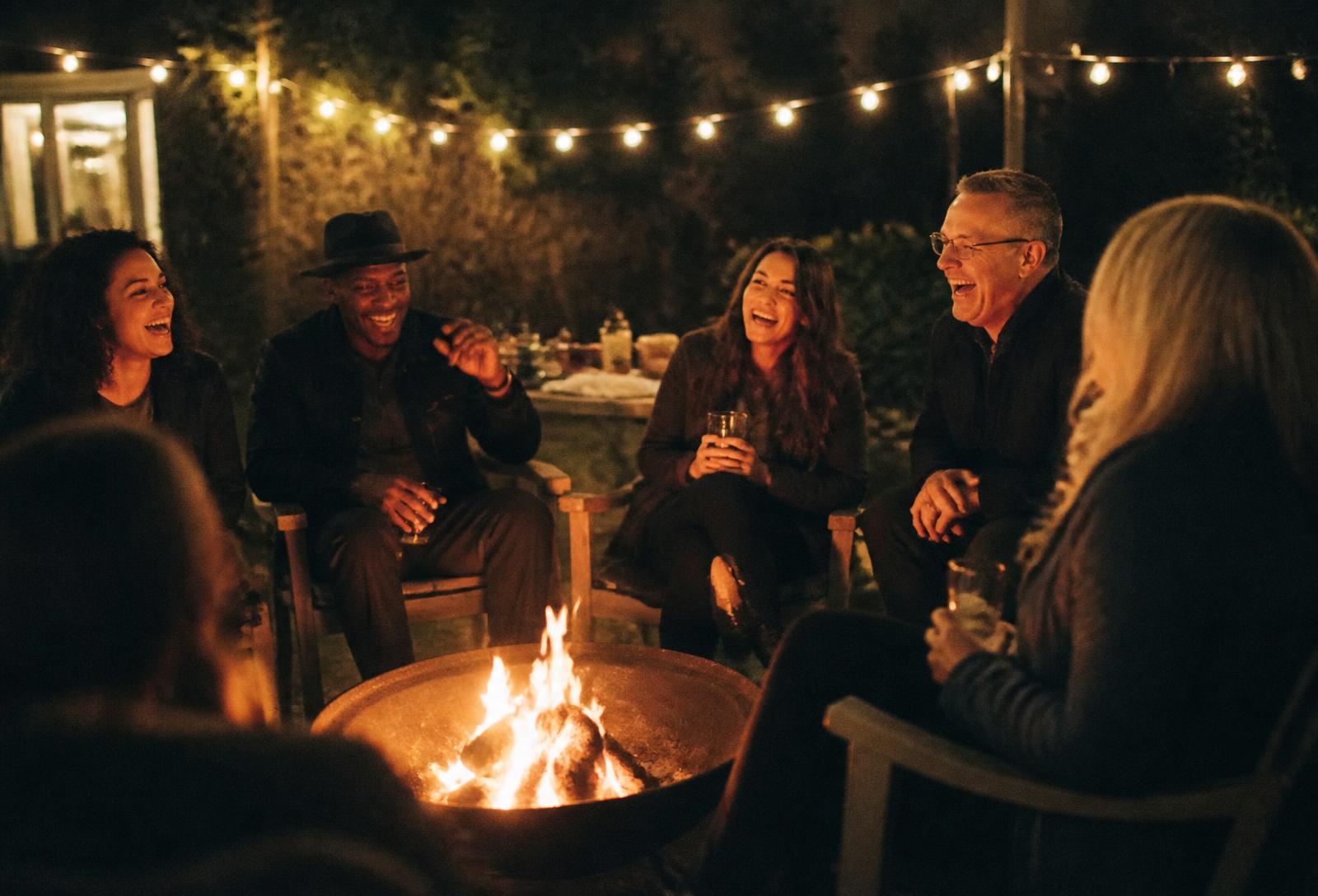 A group of friends laughing around a fire