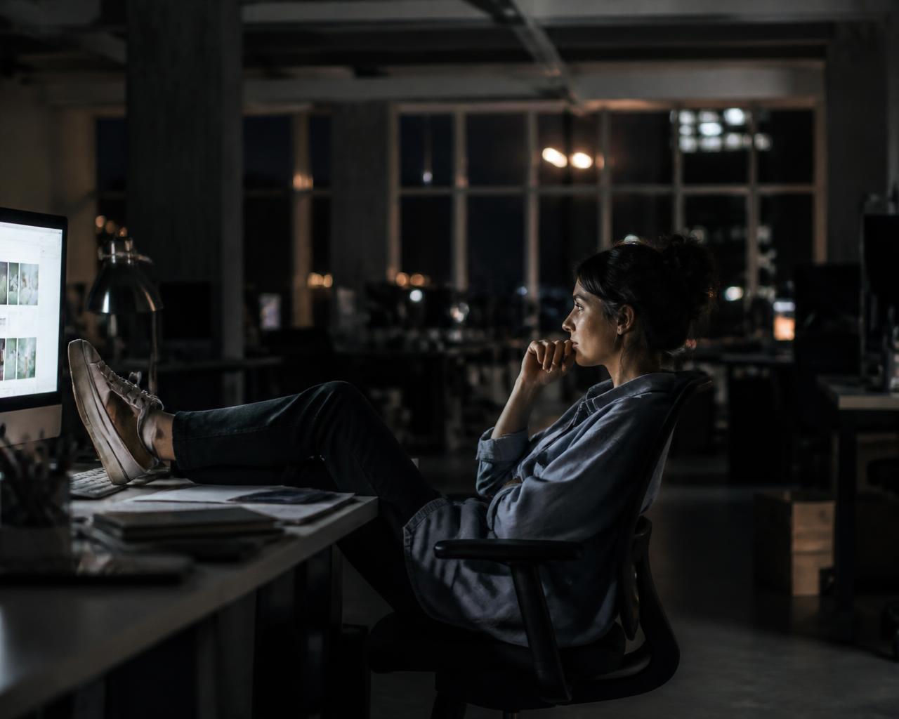 A creative director sitting alone in a dark office late at night