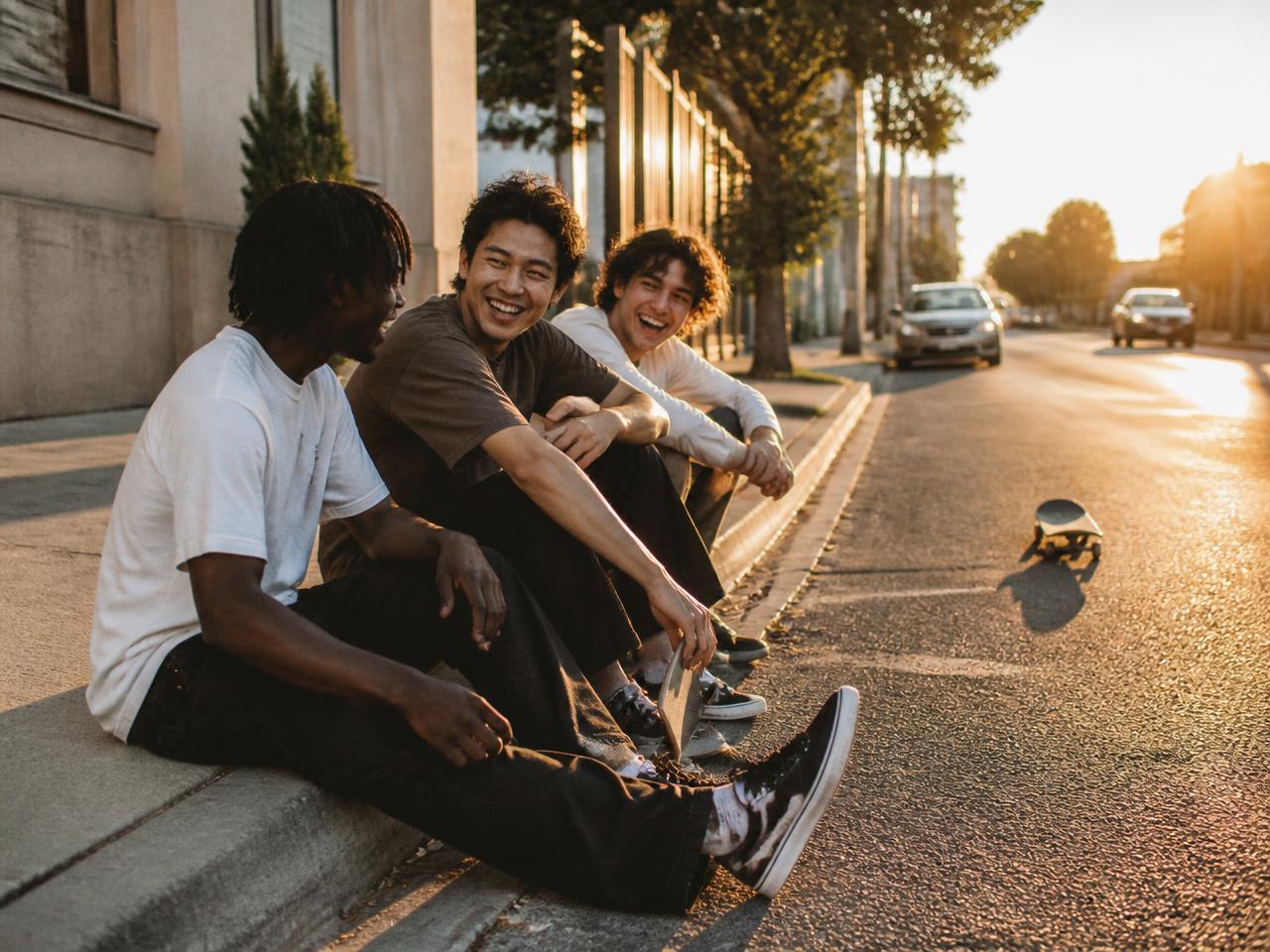 Skateboarders laughing on a curb